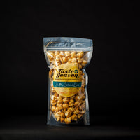 A clear stand-up pouch of Taste of Heaven Buttery Caramel Popcorn on a solid black background.