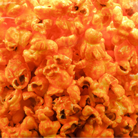 A close-up pile of bright orange popcorn kernels filling the frame.