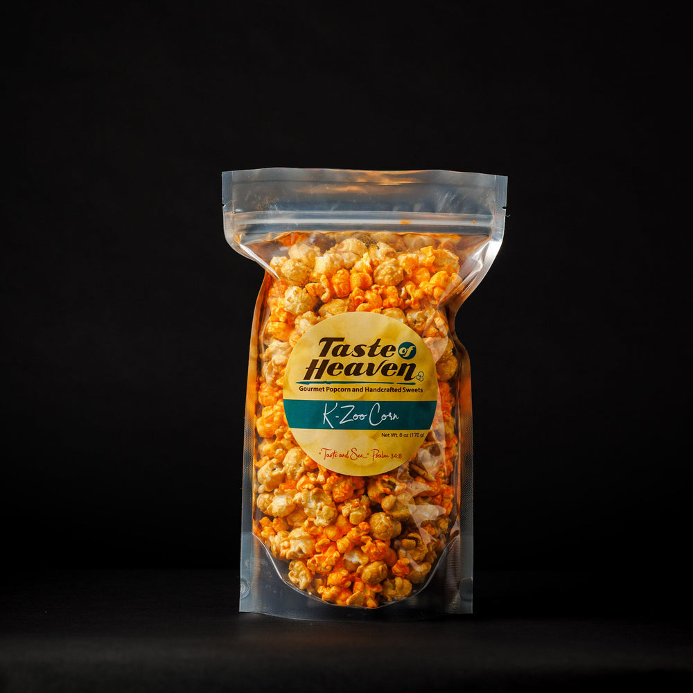 A clear stand-up pouch filled with orange-topped popcorn, centered on a black background. The front label reads Taste Heaven and K-Zoo Corn.