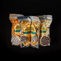 A collection of packaged food items from Taste of Heaven, including bags of caramel corn and what appears to be dipped caramel crispies and cookie pops.